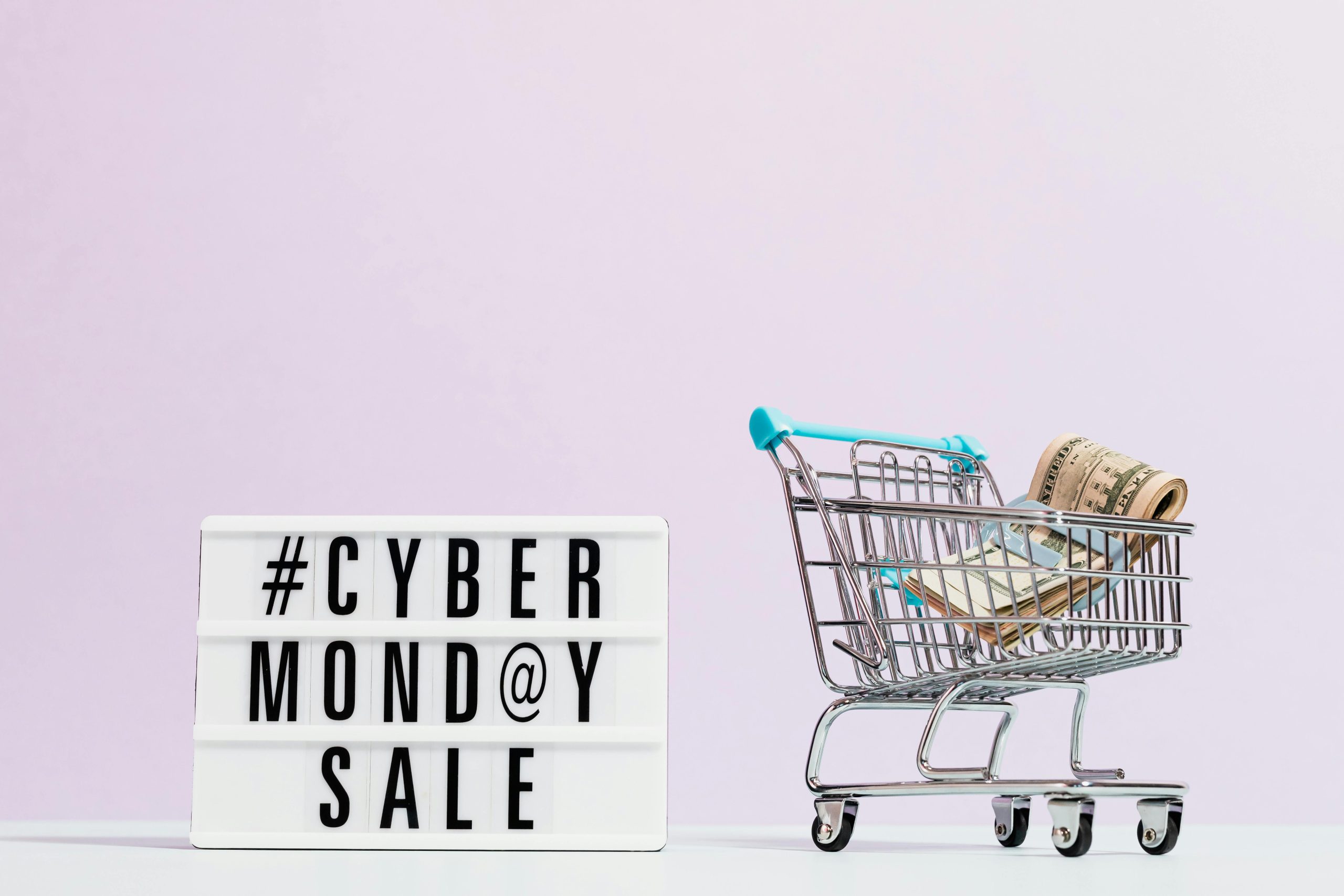 Shopping cart filled with cash beside a Cyber Monday sale sign, perfect for retail promotions.